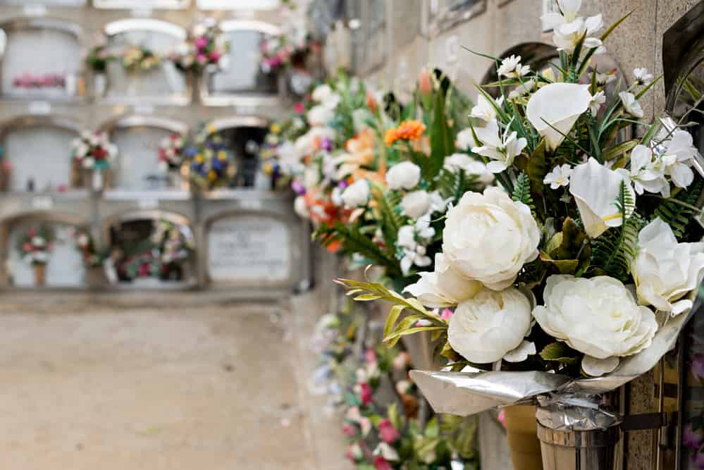 Details of tombs and burial niches in formation of several floors adorned with typical flowers of traditional Spanish cemeteries, in the local cemetery of the city of Mataro, Barcelona.