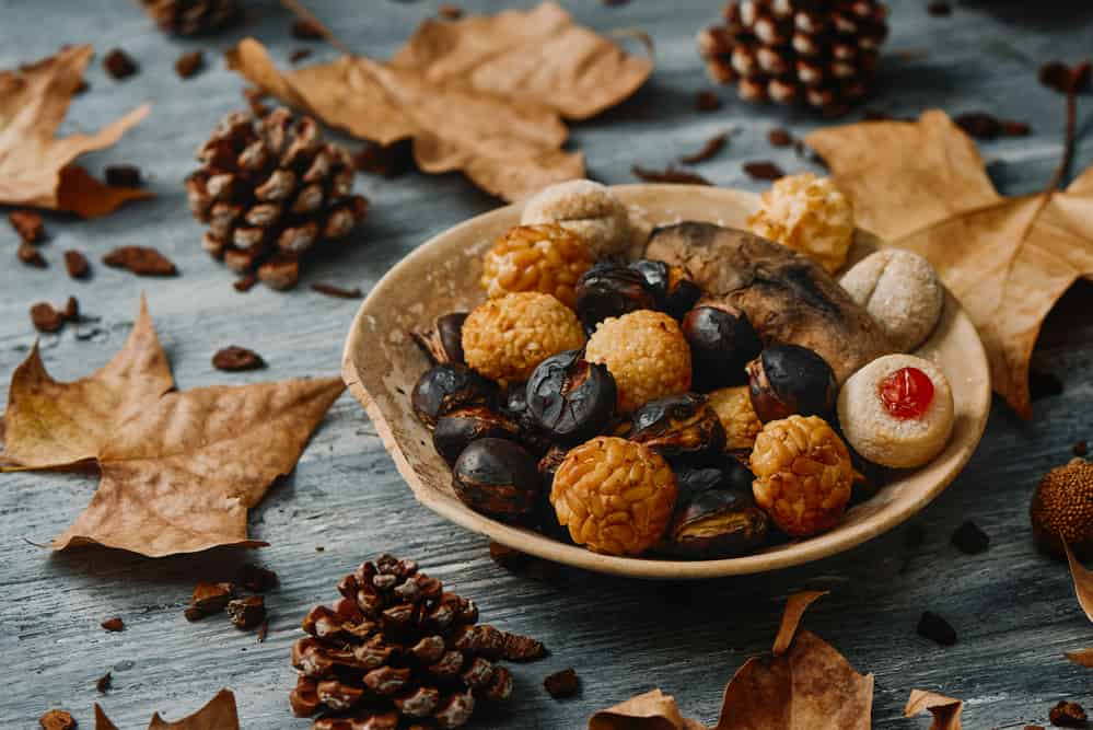 A plate with roasted sweet potato, some roasted chestnuts, and some panellets, a typical confection of Catalonia, Spain, 