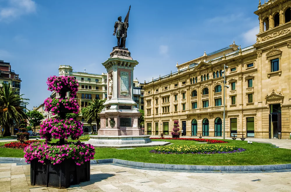 Flowers and a statue in the Picturesque square De Okendo Plaza, in San Sebastian, Northern Spain.
