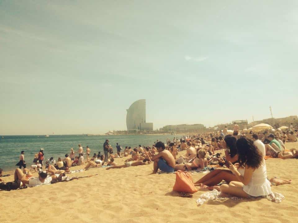 Sun-kissed beach in Barceloneta, Barcelona, with people enjoying the sand, sea, and vibrant atmosphere