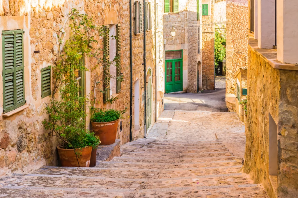 Charming cobblestone street lined with traditional Mediterranean buildings in the picturesque village of Deia, Majorca, Spain.