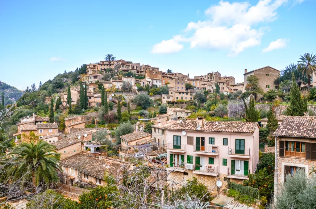 Stunning cityscape of the small coastal village Deia in Mallorca, Spain. Traditional houses located in terraces on the hills surrounded by green trees. Spanish tourist destinations.