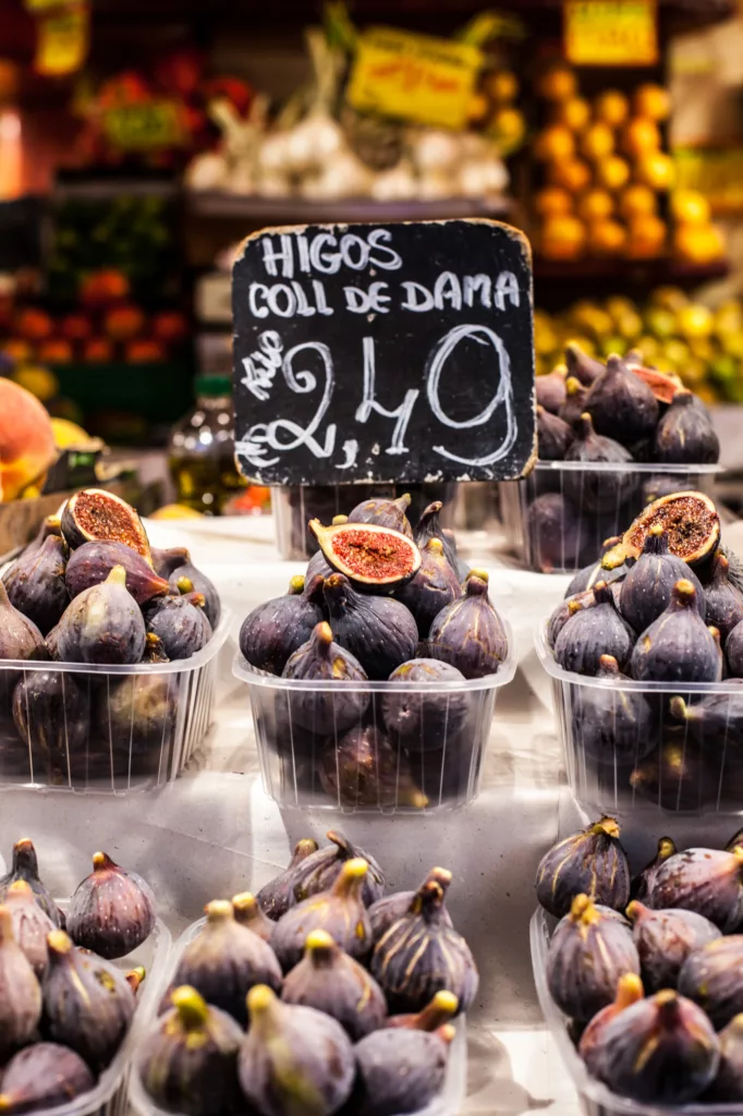 At a market stall in the Boqueria Market in Barcelona, you can find an enticing display of colorful fruits, including a variety of juicy and vibrant figs.