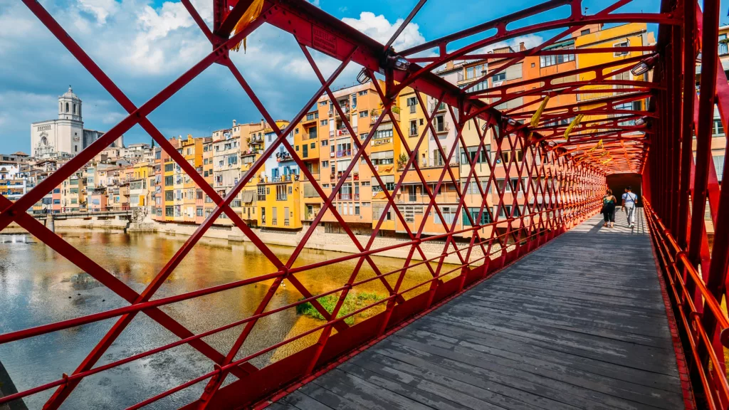Colorful houses seen through the red iron bridge in Girona, Catalonia, Spain