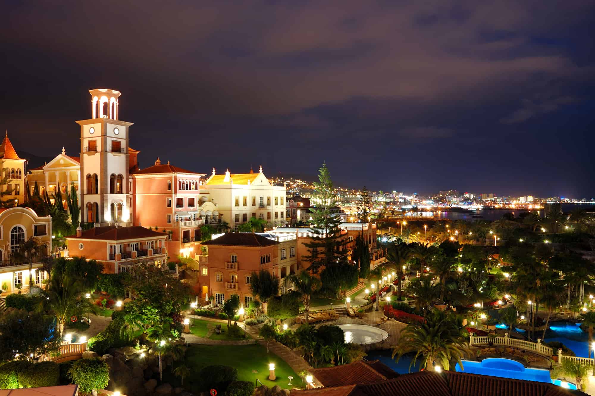 Night illumination of luxury hotel during sunset and Playa de las Americas at background, Tenerife island, Spain