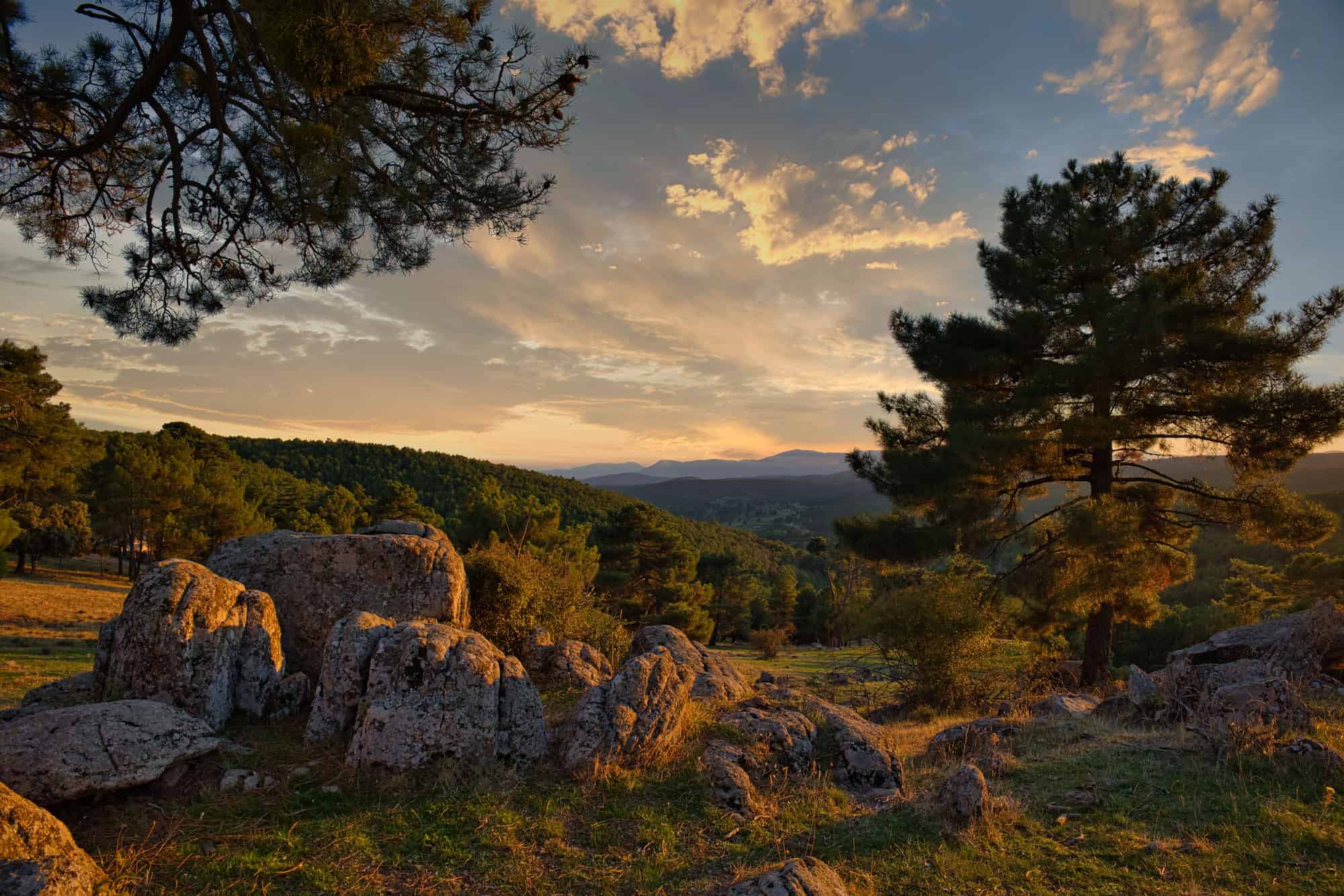 An aerial view of a golden sunset over rocky forests and mountains in the Spanish Countryside