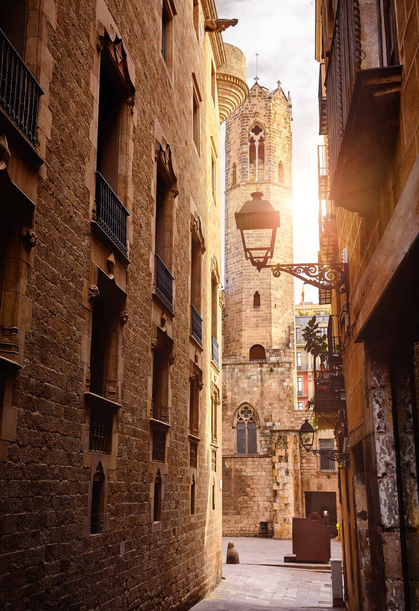 Gothic Quarter in Barcelona Catalonia Spain. Vew at ancient tower. Antique lamps on the narrow streets with medieval buildings. Ancient architecture of old town stone houses. Evening sky and antique street lanterns