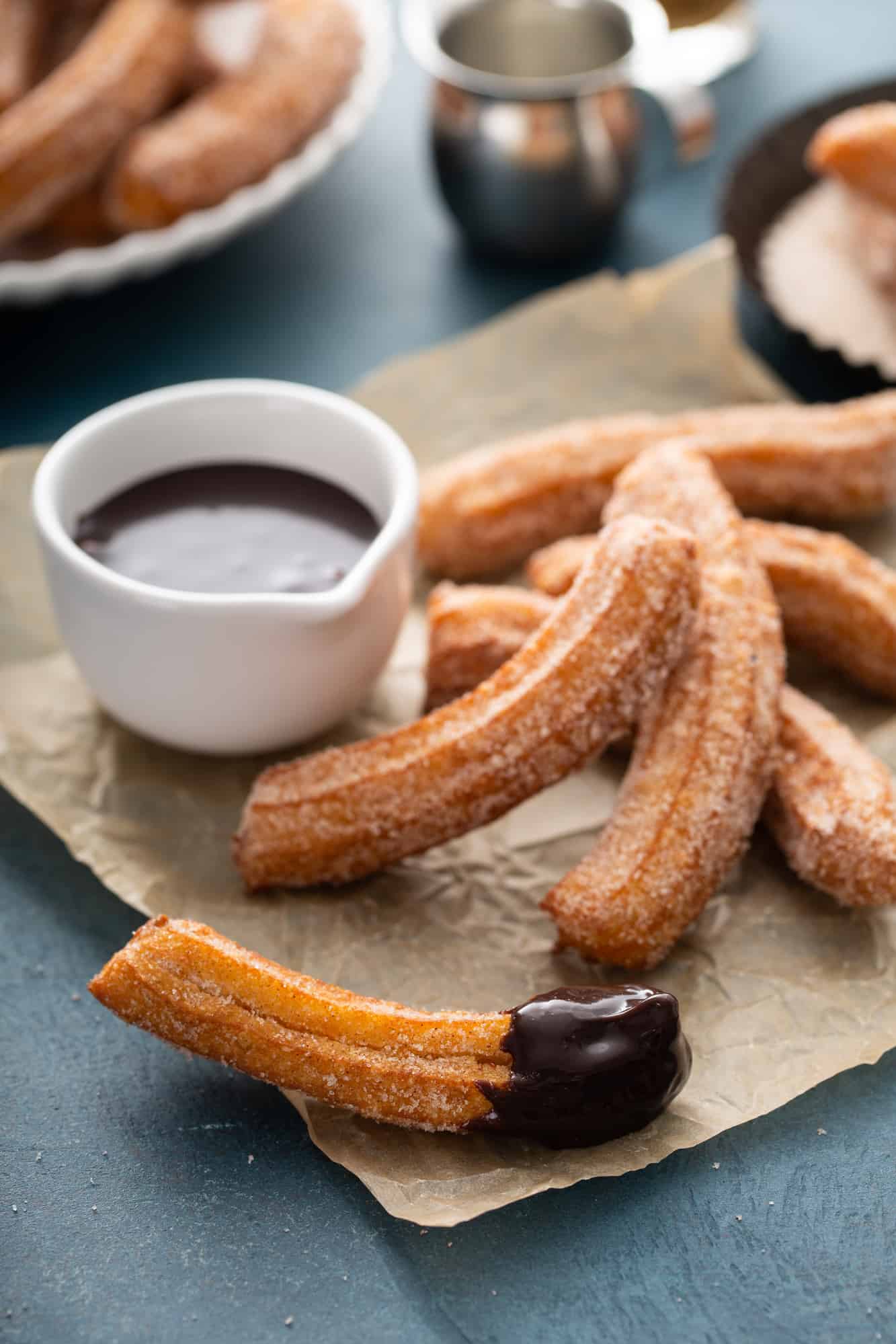 Spanish churros with cinnamon sugar and chocolate on parchment