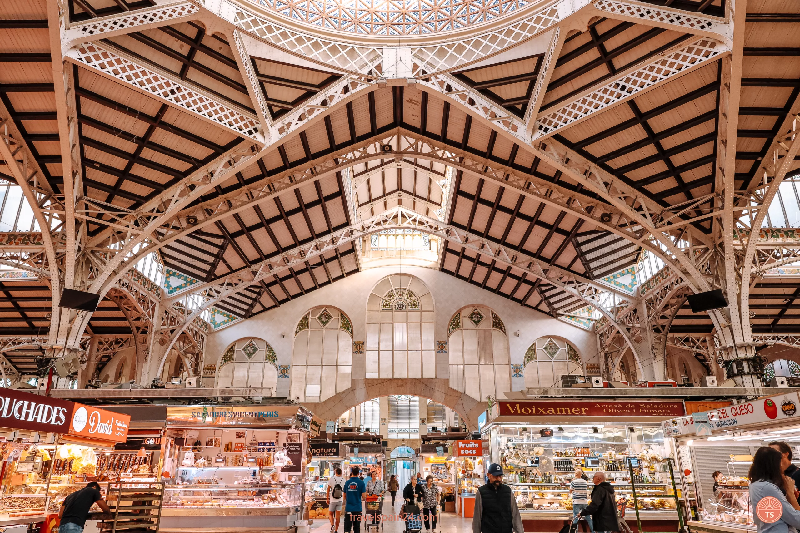 Inside view of the Central Market of Valencia with its special roof, bright walls, sunlight through windows, and market stalls.