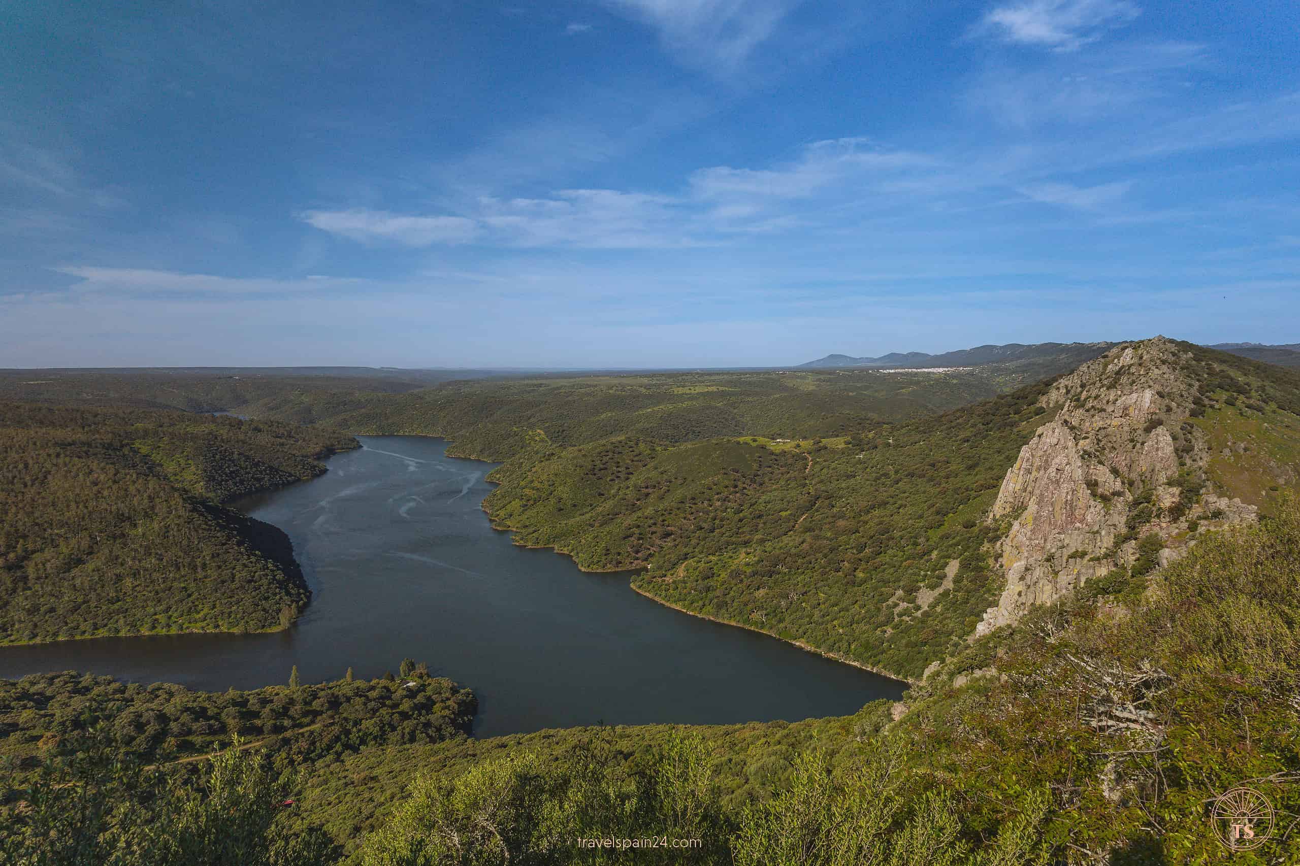 Morning view of Peña Falcón rock formation from the castle in Monfragüe National Park, featuring a clear blue sky and the river in the distance.