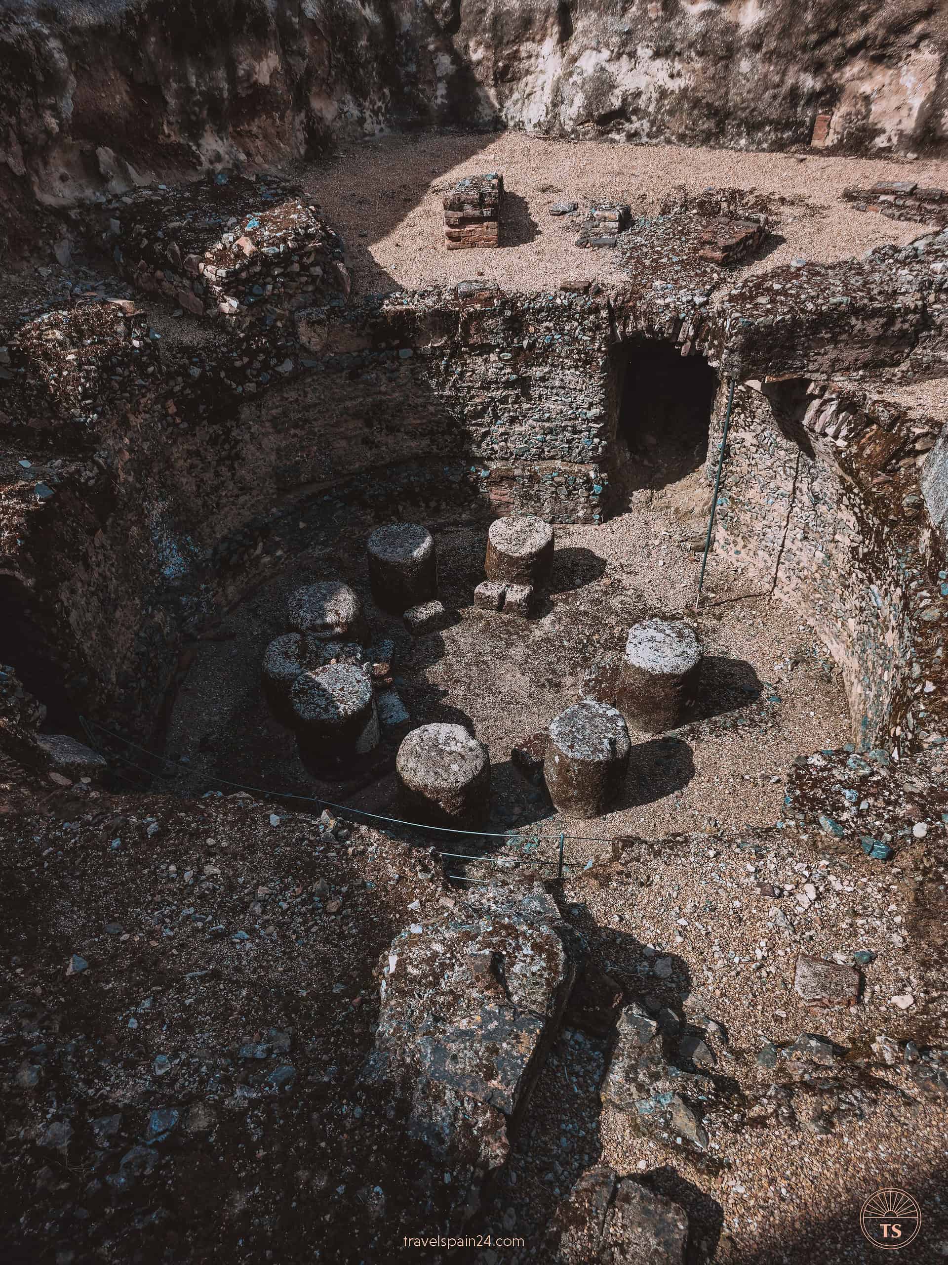 Ancient Termas Romanas de la Nieve in Mérida, featuring seven small stone pillars arranged in a circle, remnants of Roman baths.