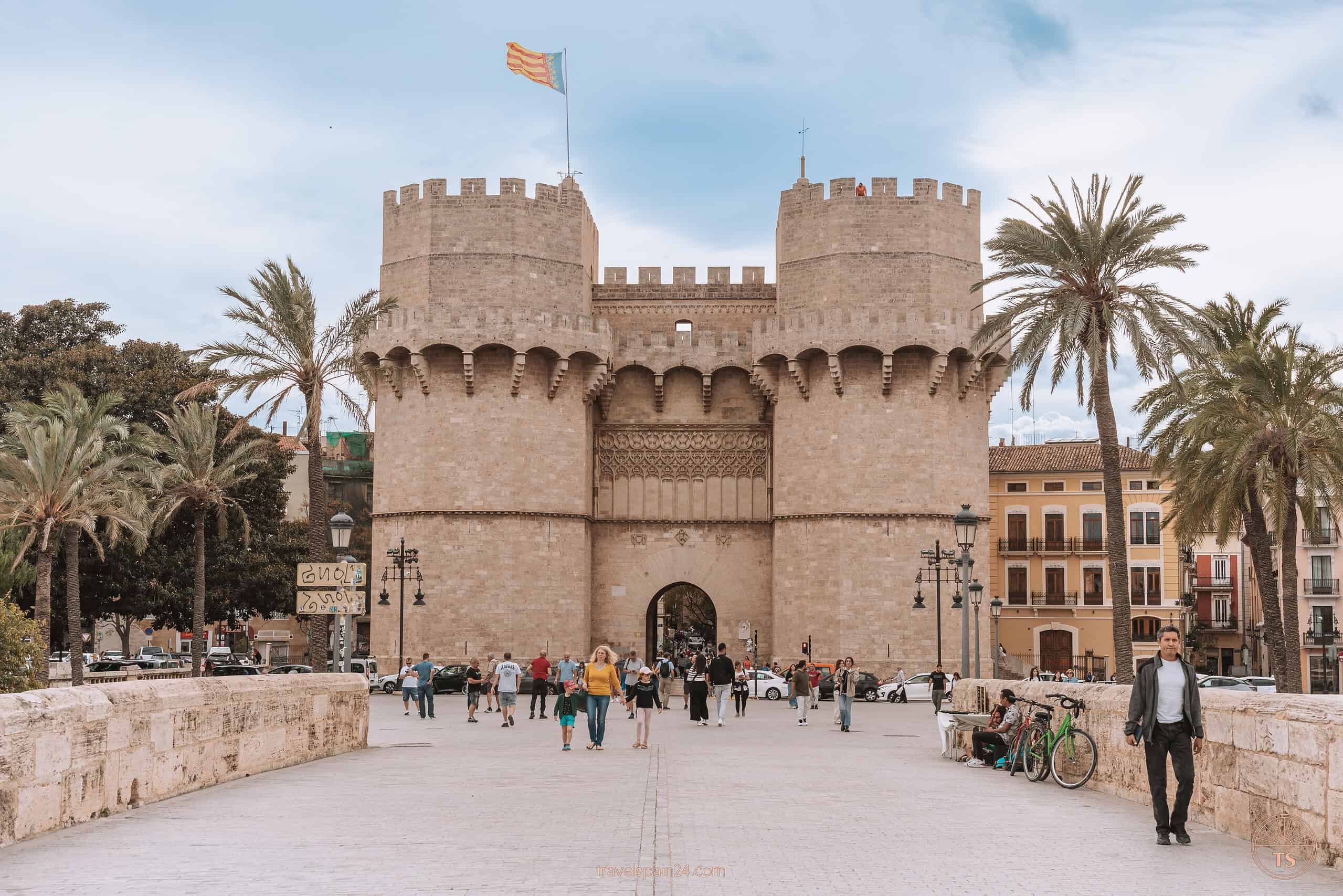 View from the bridge of the Serranos Towers in Valencia, showing many people walking through the open doors into the city center—a bustling gateway to explore this must-visit attraction.