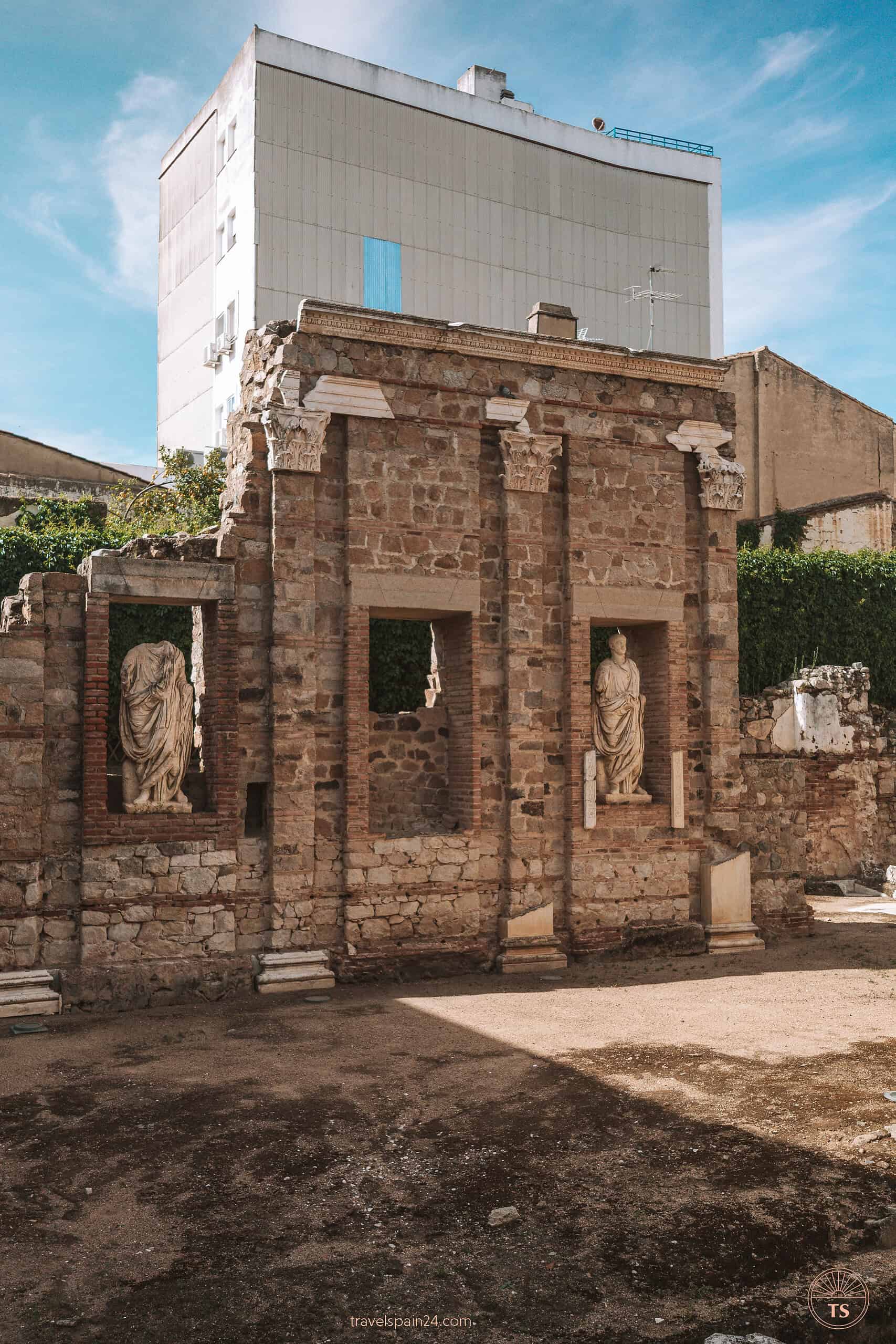 Ancient Roman ruins with statues along a central street at Pórtico del Foro Municipal de Augusta Emérita in Mérida, capturing the city's rich historical past.