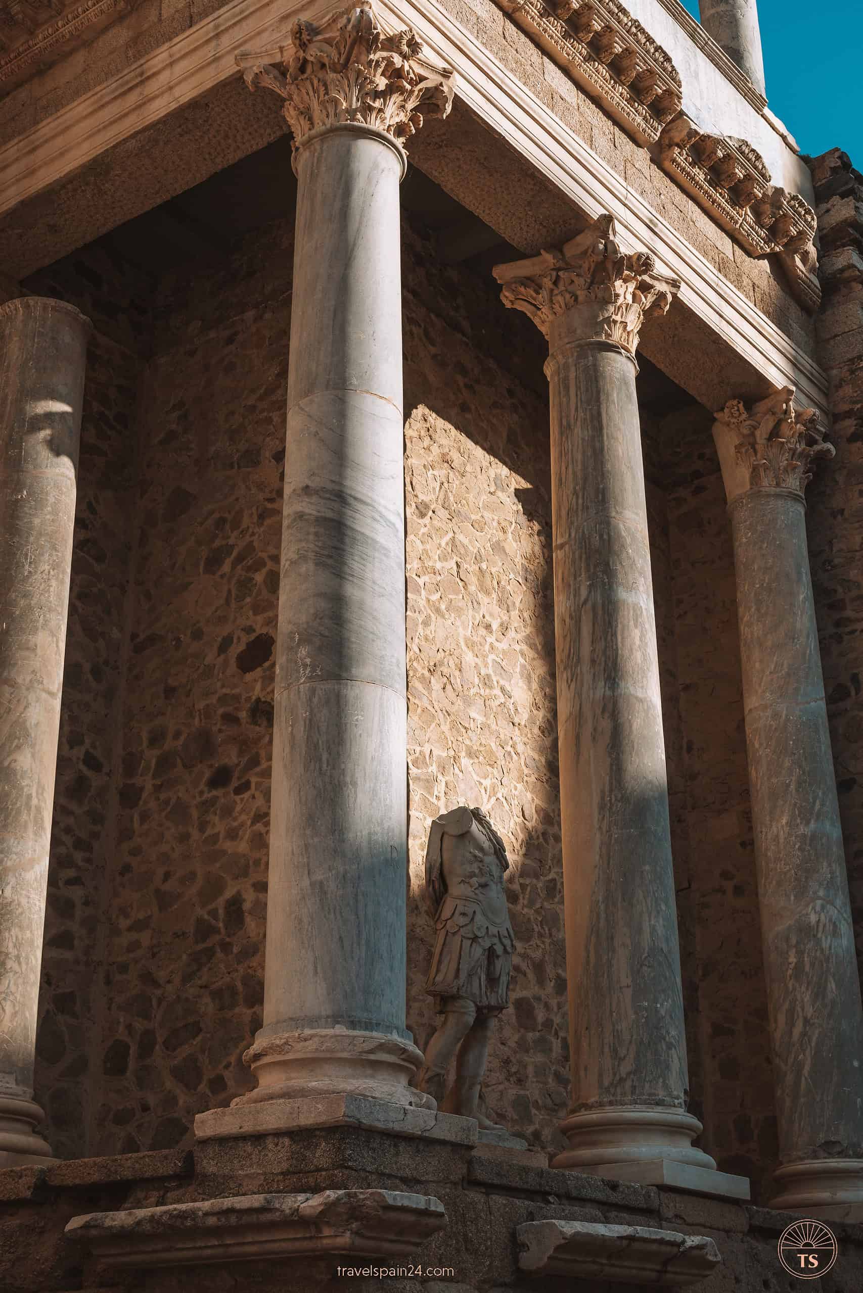 Close-up of the pillars at the Roman Theatre in Mérida, featuring a weathered Roman statue between columns, showcasing the architectural heritage of the city