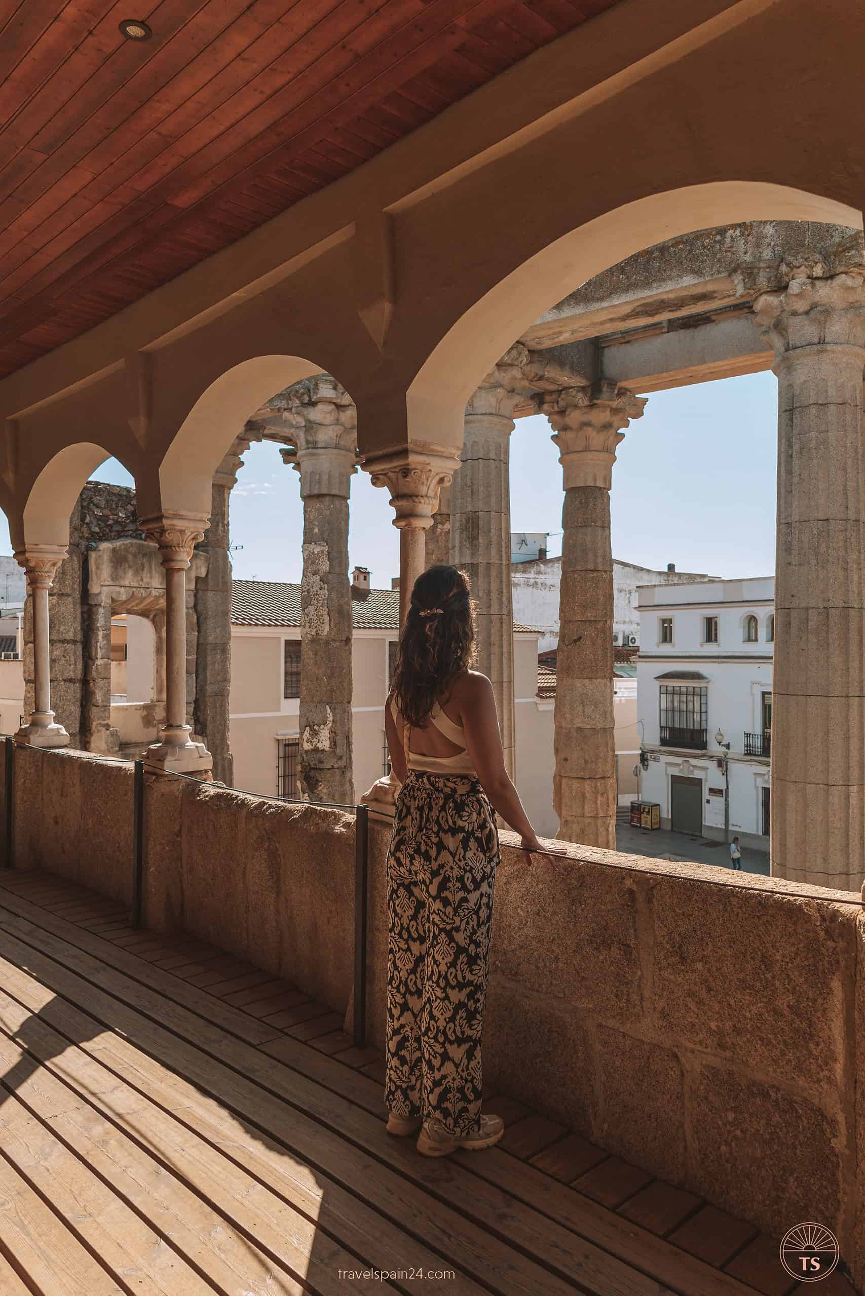 Filipa Ferreira standing on a balcony at Palacio de los Corbos in Mérida, overlooking the Temple of Diana, enjoying the sunny day and the historical view.
