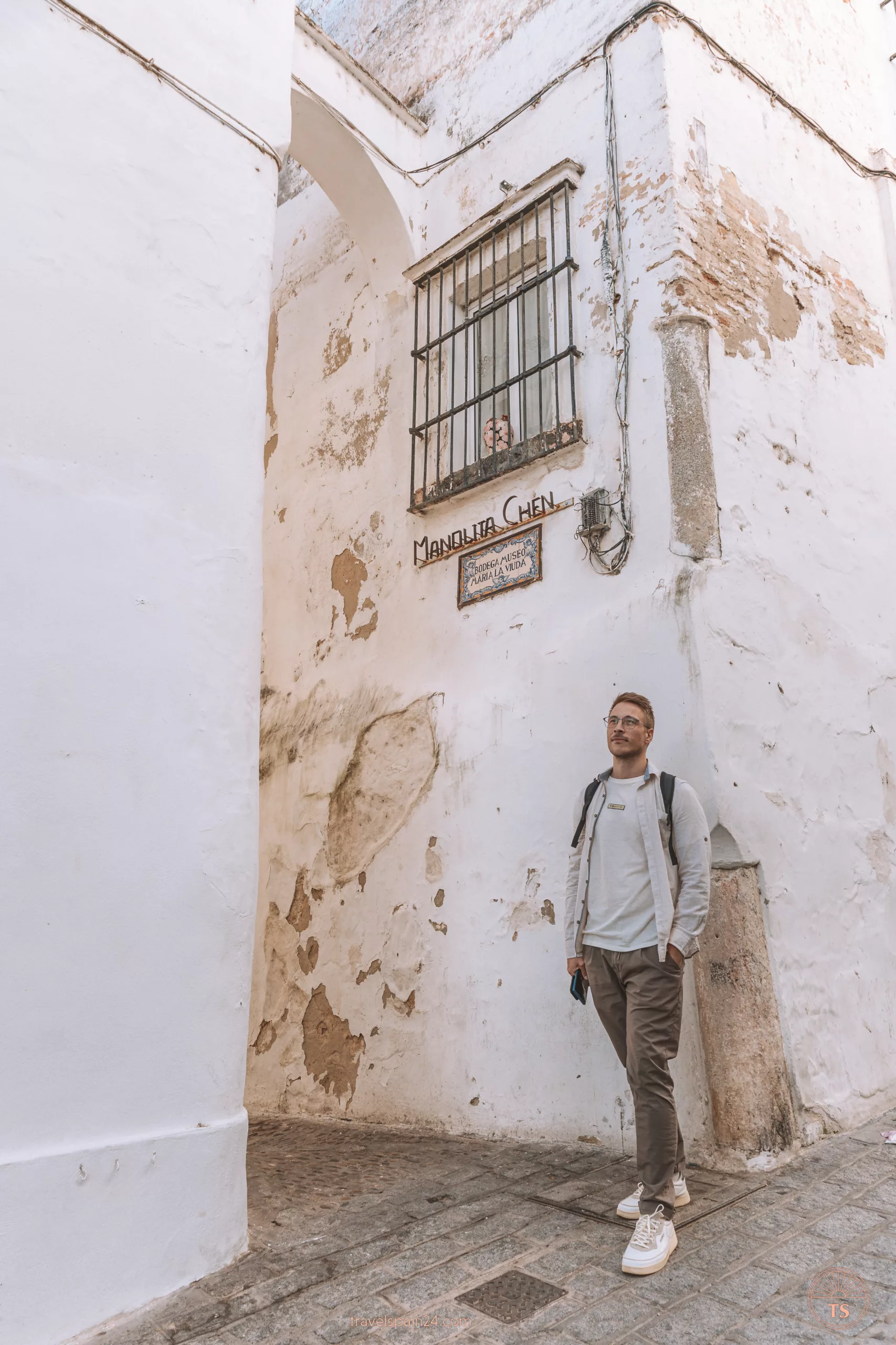 Timon van Basten stands in one of Arcos de la Frontera's charming white alleys. The walls are white, showing chipped cement, reflecting the village's age.