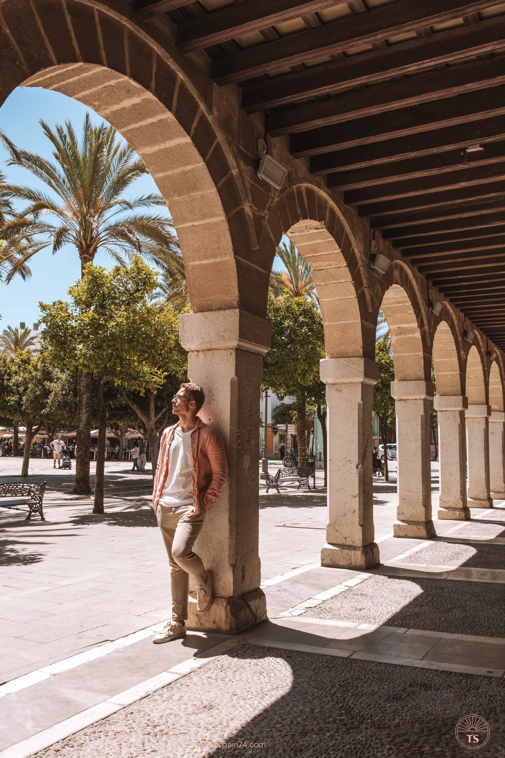 Timon van Basten leaning against an arch of a building in Jerez de la Frontera, with a view of the plaza in the background. This image captures the charm of exploring the city's streets.