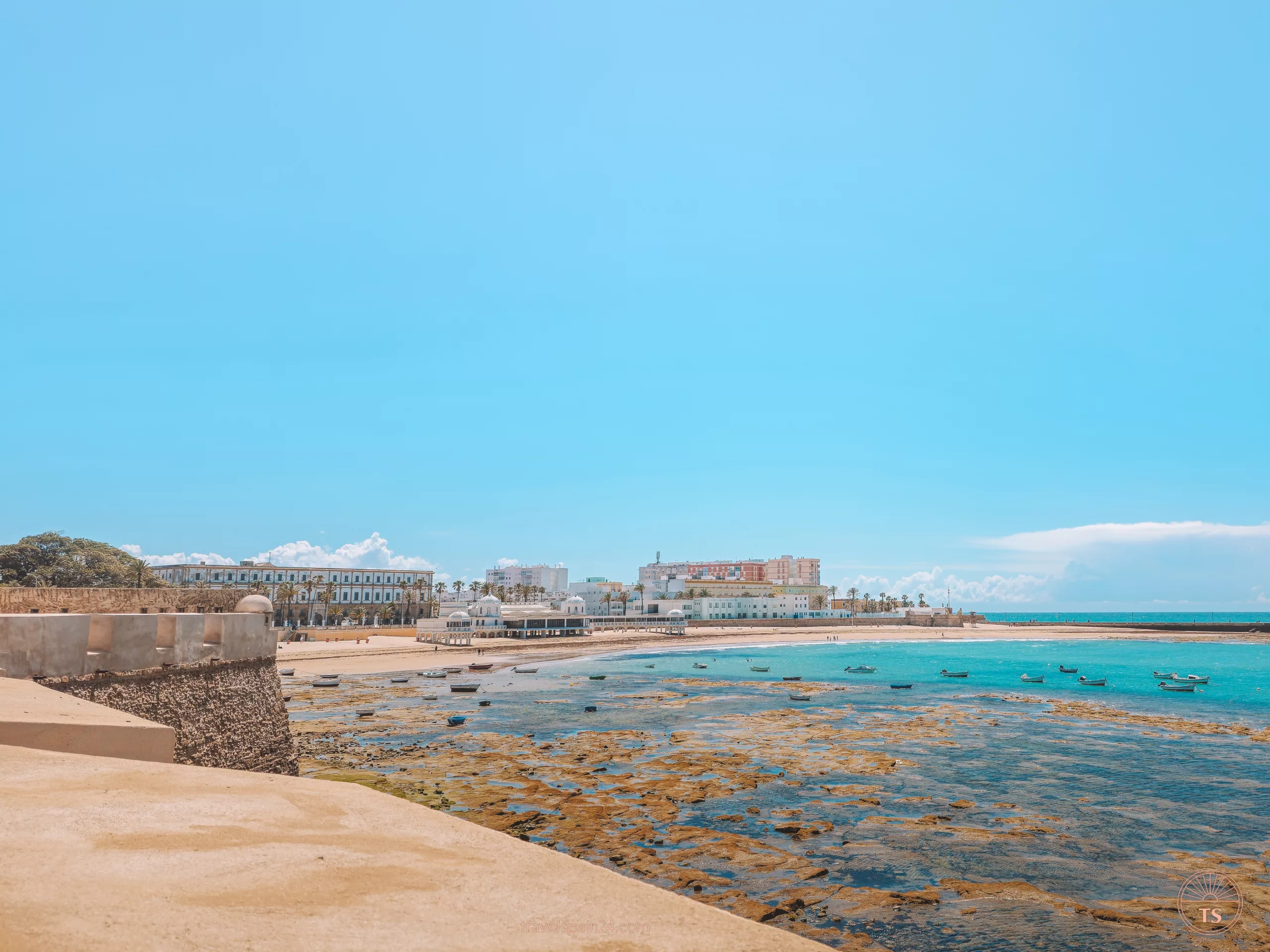 View of Caleta Beach from the castle in Cadiz, including Balneario de Nuestra Señora de la Palma y del Real. This perspective is one of the Cadiz highlights, capturing the scenic beauty and historical landmarks of the coastline.
