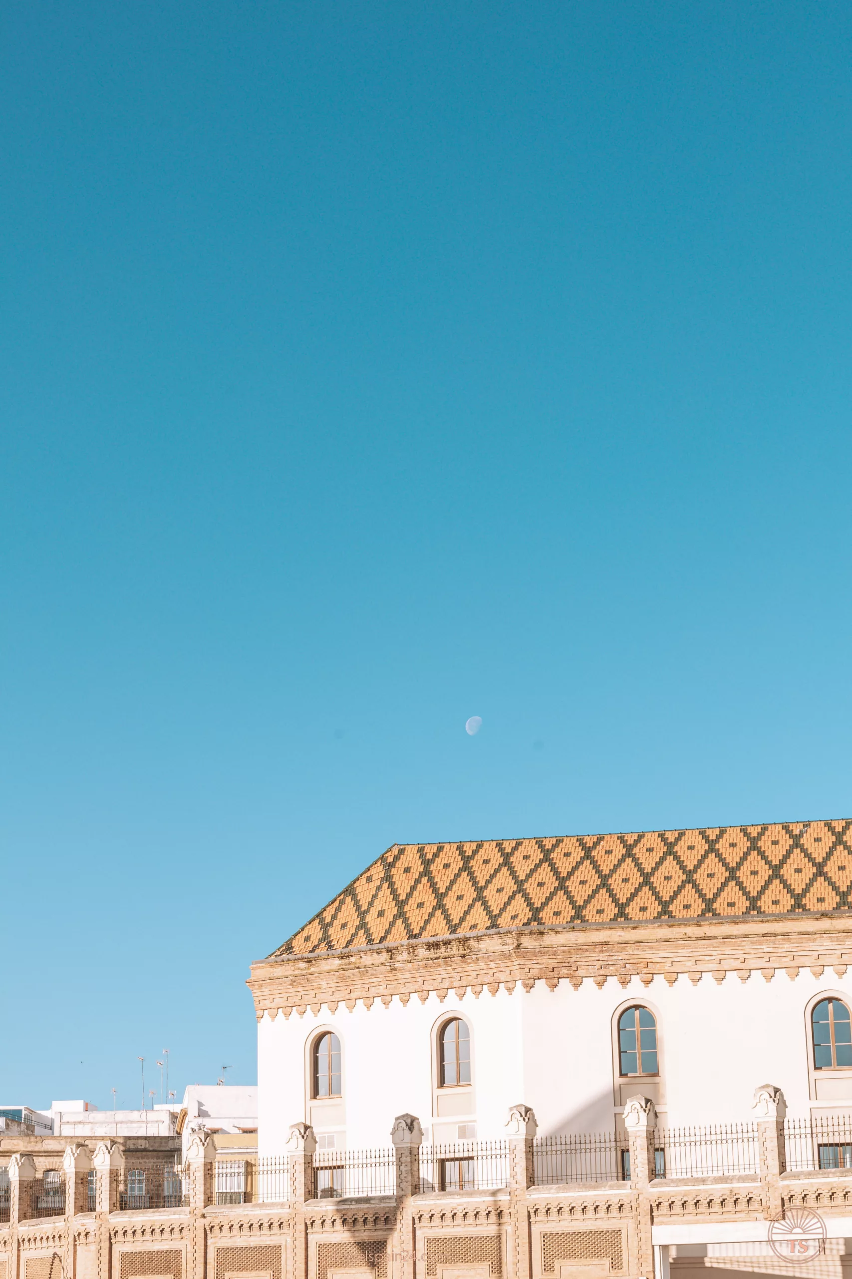 View of the Palacio de Congresos de Cádiz on a sunny morning, with the moon still visible in the sky. This image captures the architectural beauty of this landmark in Cadiz
